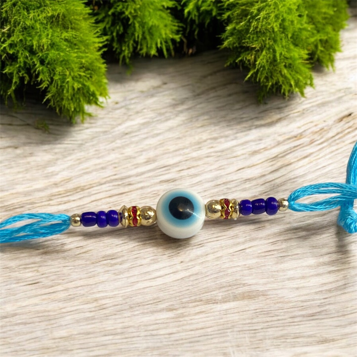 White Evil Eye Rakhi with Light Blue Thread & Gold Beads – Rakhi for Brother | Handmade Rakhi UK