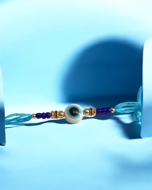 White Evil Eye Rakhi with Light Blue Thread & Gold Beads – Rakhi for Brother | Handmade Rakhi UK